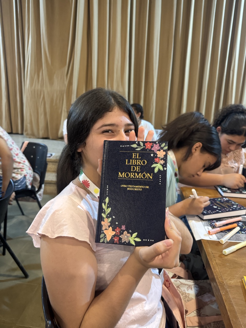 Participante de Campalma mostrando un ejemplar decorado del Libro de Mormón