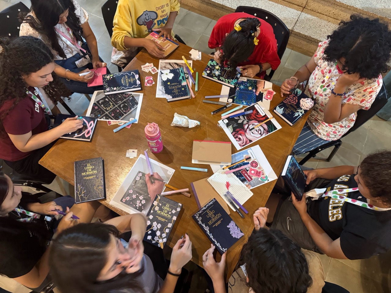 Participantes decorando ejemplares del Libro de Mormón alrededor de una mesa